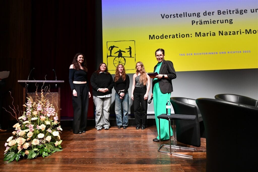 Hochwertige Veranstaltung der Richterinnen und Richter auf der Bühne mit Präsentationen und Ehrungen, Fokus auf Rechtsprechung und Gemeinschaft.